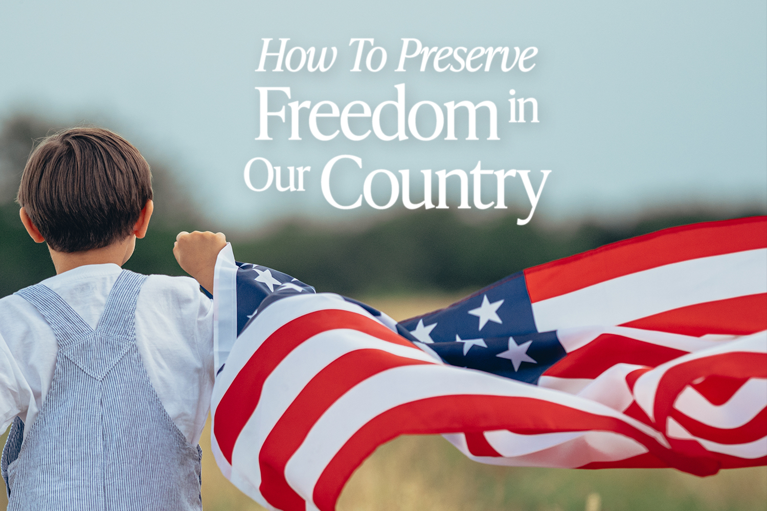 Young Child Holding an American flag in a field with blue sky