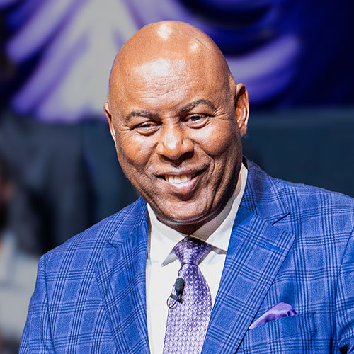 Keith Butler smiling while speaking in a church, with a purple and gray background